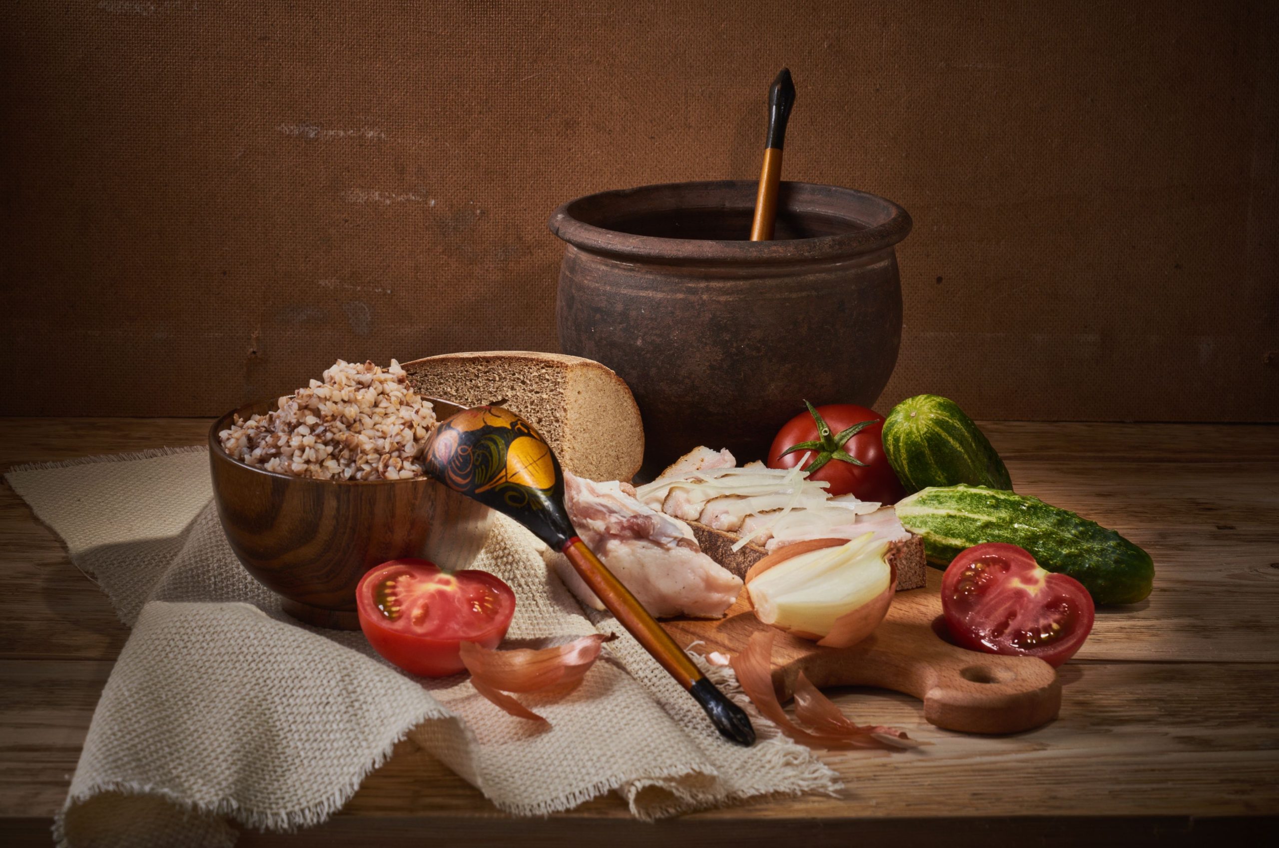 Cozy rustic still life featuring buckwheat, vegetables, and traditional tableware on a wooden surface.